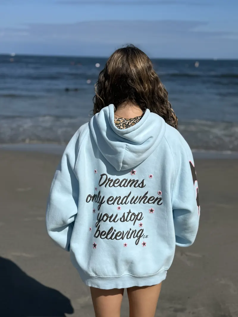 The back of the hoodie: Dreams only end when you stop believing, in script with small stars