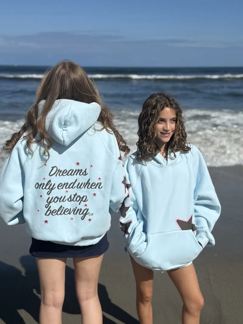 Chyler and a friend on the beach in the light blue hoodie, one showing the front and one showing the quote on the back